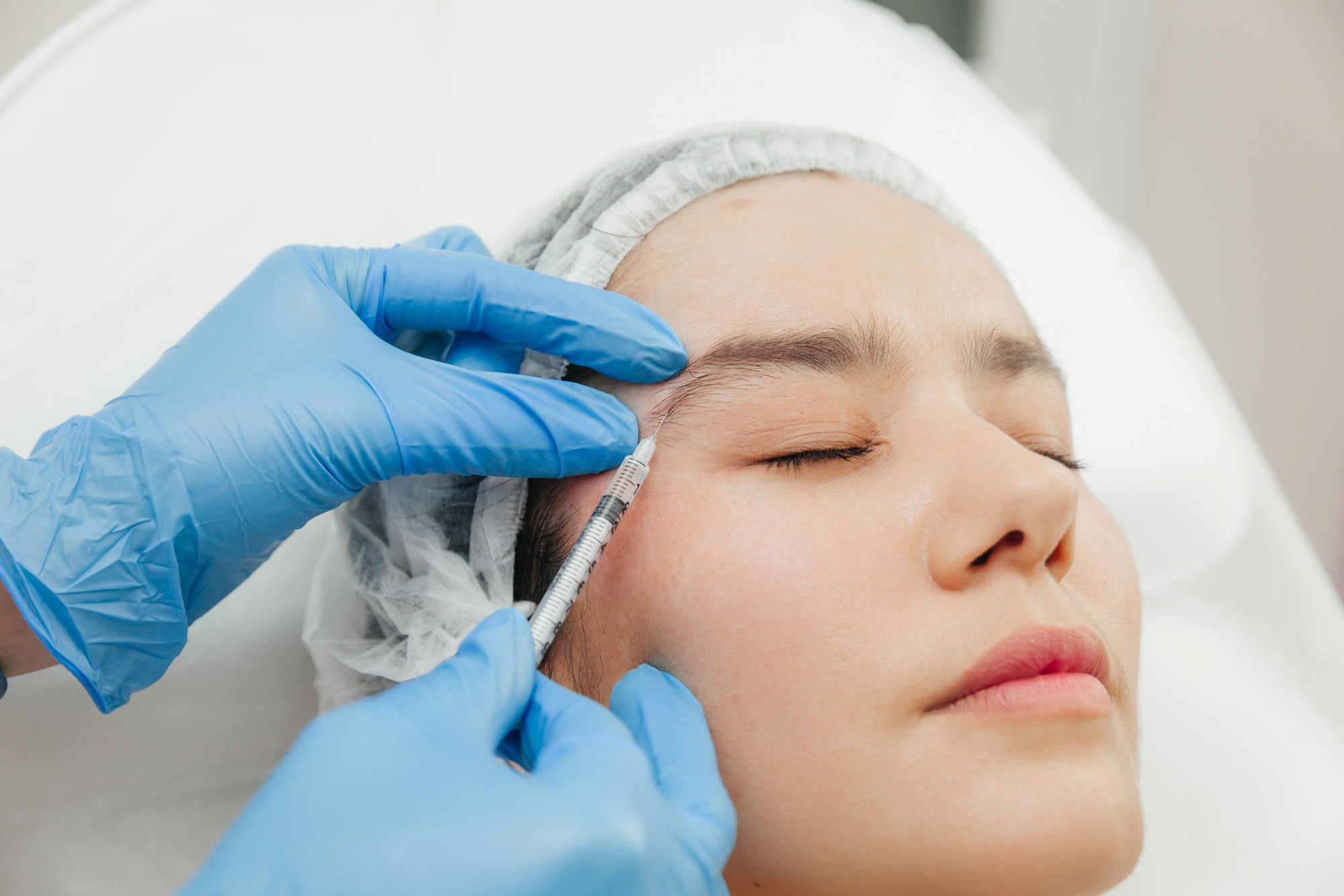 Close up of the hands of a beautician injecting botox into a woman s forehead .jpg