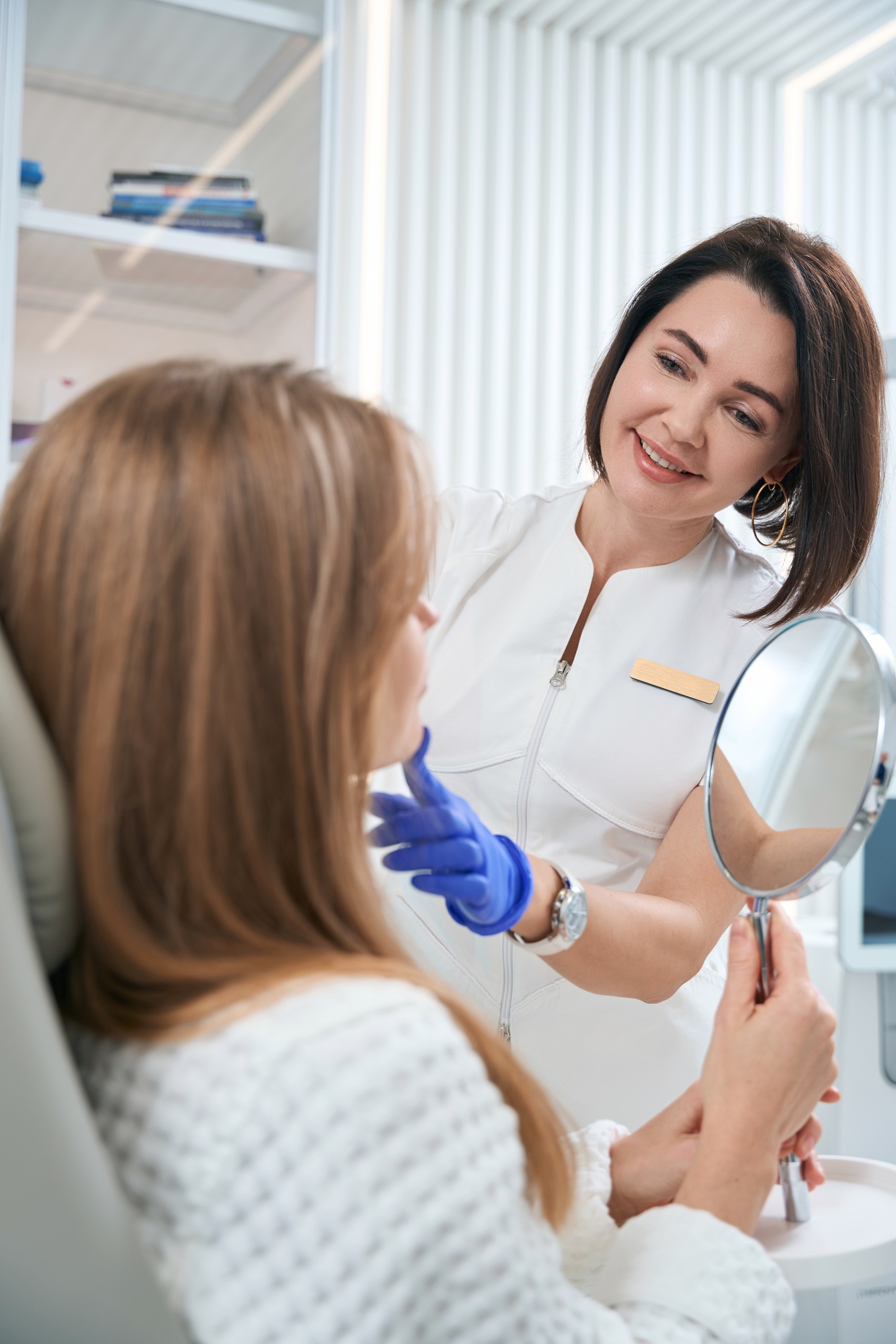 Woman sits in chair and holdsa mirror in her hands.jpg